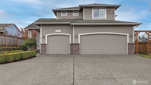 garage featuring concrete driveway and fence