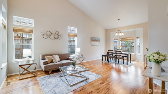 living room with visible vents, high vaulted ceiling, a notable chandelier, light wood finished floors, and baseboards