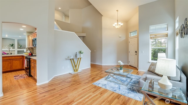 living room featuring a notable chandelier, recessed lighting, light wood finished floors, and high vaulted ceiling