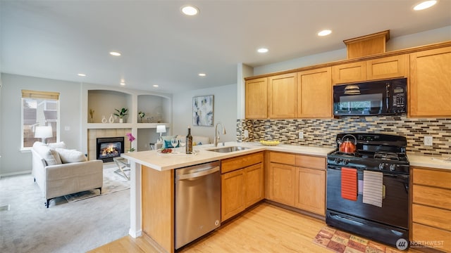 kitchen with black appliances, a peninsula, light countertops, and a sink