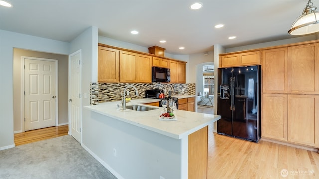 kitchen featuring tasteful backsplash, recessed lighting, light wood-style floors, black appliances, and a sink