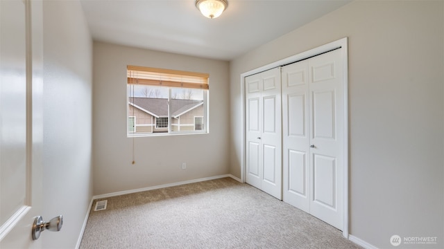 unfurnished bedroom with a closet, baseboards, visible vents, and carpet floors