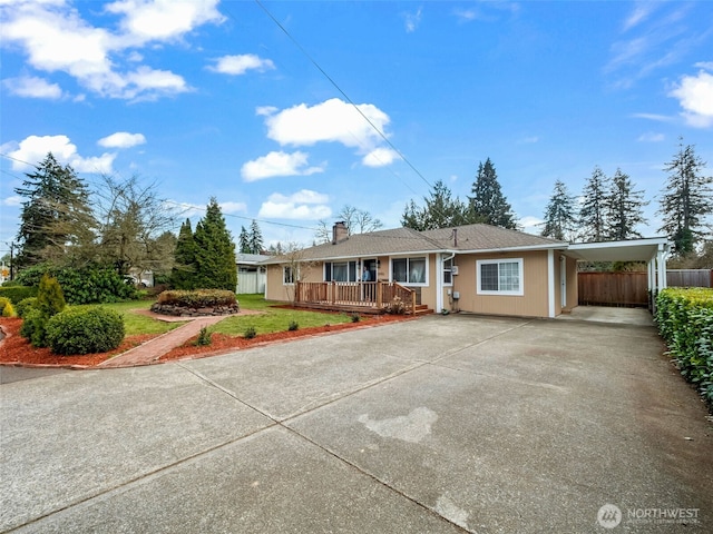 ranch-style house featuring an attached carport, a front lawn, fence, a chimney, and driveway