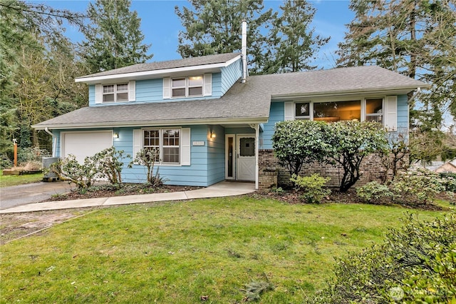 split level home featuring a front lawn, an attached garage, driveway, and a shingled roof