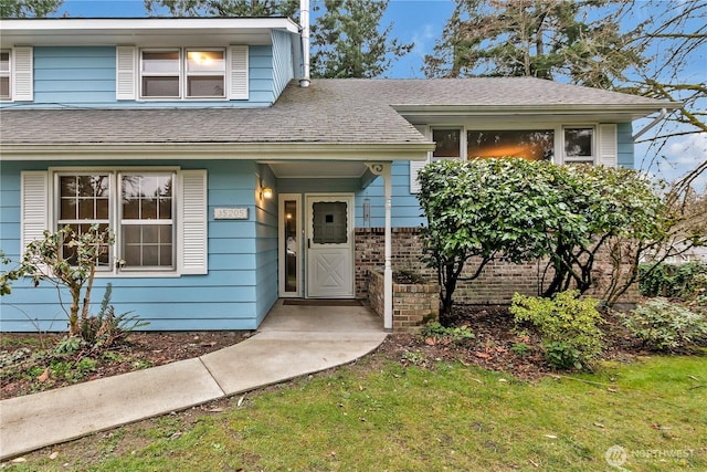 tri-level home with brick siding, roof with shingles, and a front yard