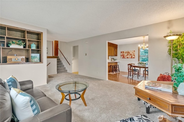 living area featuring stairway, carpet floors, a textured ceiling, and an inviting chandelier