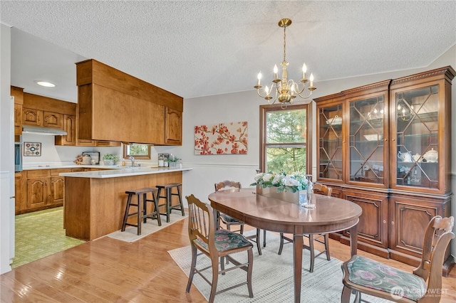 dining room featuring an inviting chandelier, light wood-style flooring, and a textured ceiling