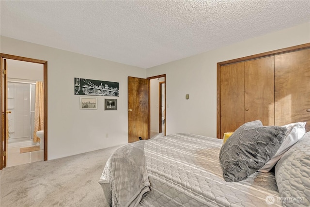 carpeted bedroom with ensuite bath, a closet, and a textured ceiling