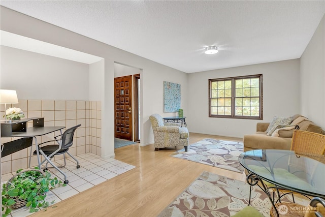 living area featuring baseboards, light wood-style floors, and a textured ceiling