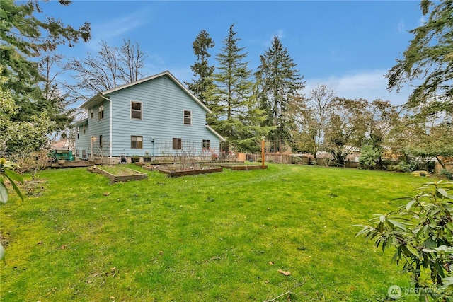 rear view of property with a garden, a lawn, and fence