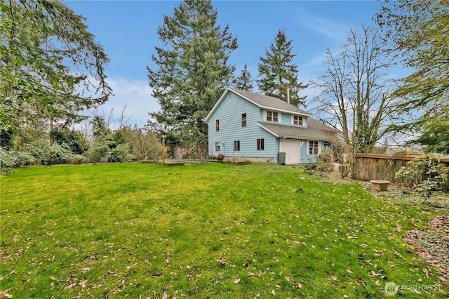 rear view of property featuring a lawn and fence