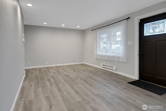 entrance foyer featuring baseboard heating, plenty of natural light, and light wood-type flooring