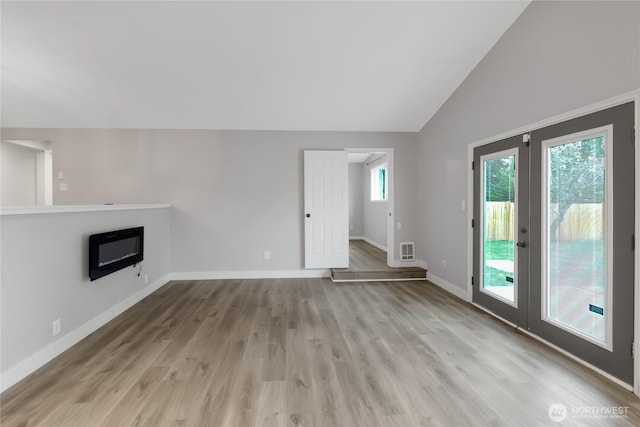 unfurnished living room featuring visible vents, lofted ceiling, wood finished floors, french doors, and baseboards