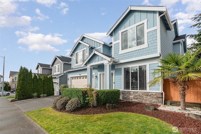 view of front of house with stone siding, an attached garage, board and batten siding, and driveway