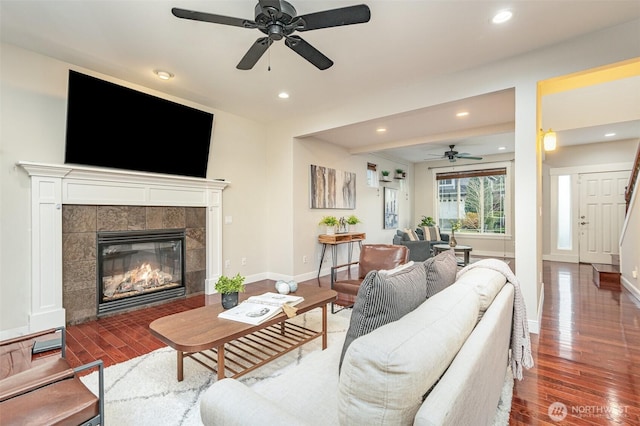 living area with a tiled fireplace, recessed lighting, baseboards, and wood finished floors