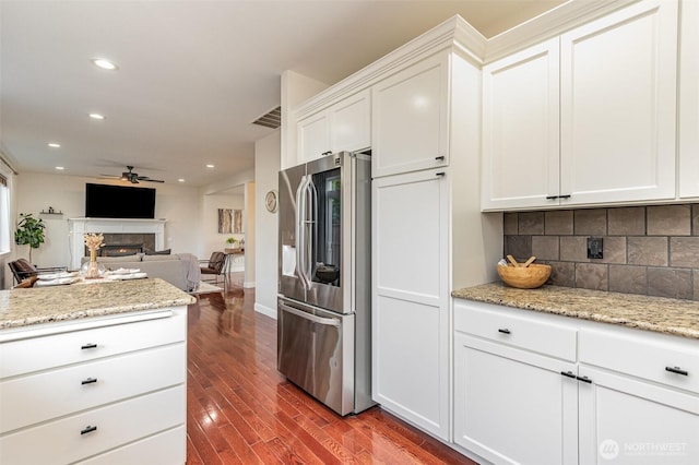 kitchen with visible vents, backsplash, stainless steel fridge with ice dispenser, a lit fireplace, and dark wood-style flooring