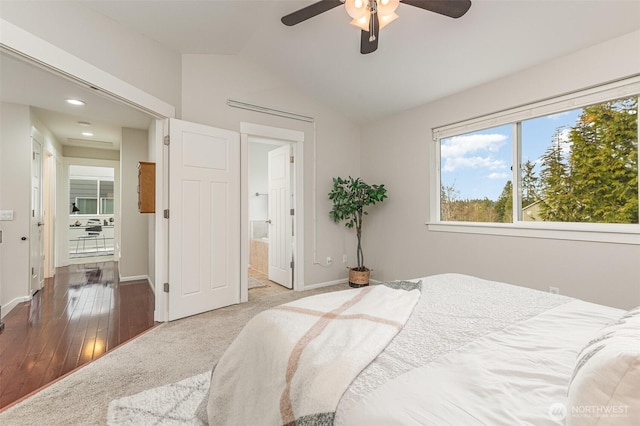 carpeted bedroom with connected bathroom, lofted ceiling, baseboards, and a ceiling fan