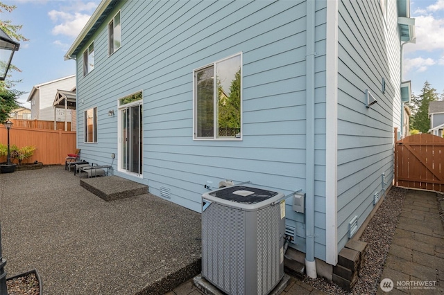 back of house featuring a gate, fence, crawl space, central AC unit, and a patio area