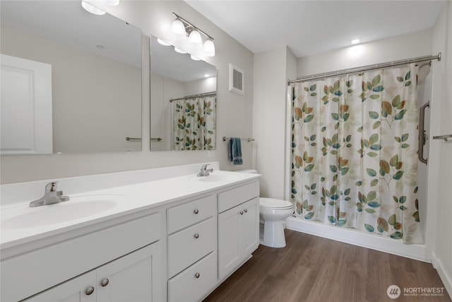 full bathroom featuring double vanity, wood finished floors, toilet, and a sink