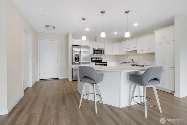 kitchen with a center island, light countertops, appliances with stainless steel finishes, white cabinetry, and a sink