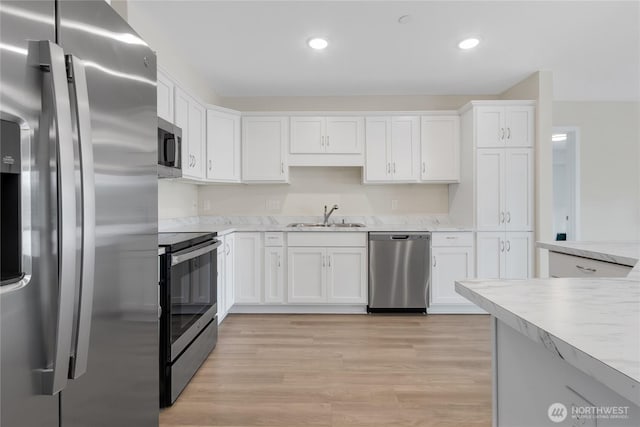 kitchen featuring recessed lighting, a sink, appliances with stainless steel finishes, white cabinetry, and light wood-type flooring