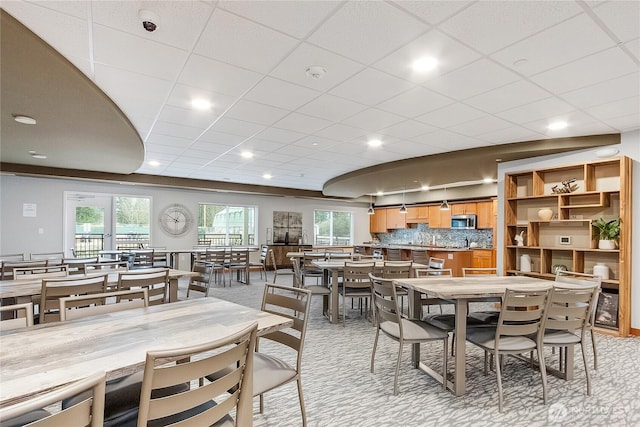 dining space with light carpet and a drop ceiling