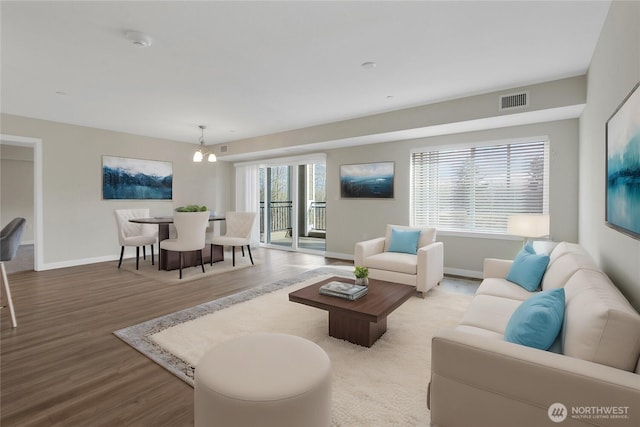 living area with wood finished floors, visible vents, and baseboards