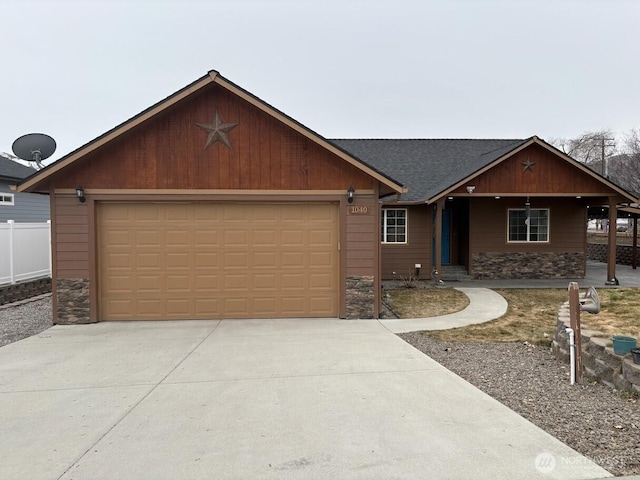 view of front facade featuring fence, driveway, roof with shingles, a garage, and stone siding