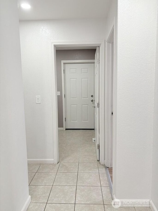 hall with light tile patterned flooring and baseboards