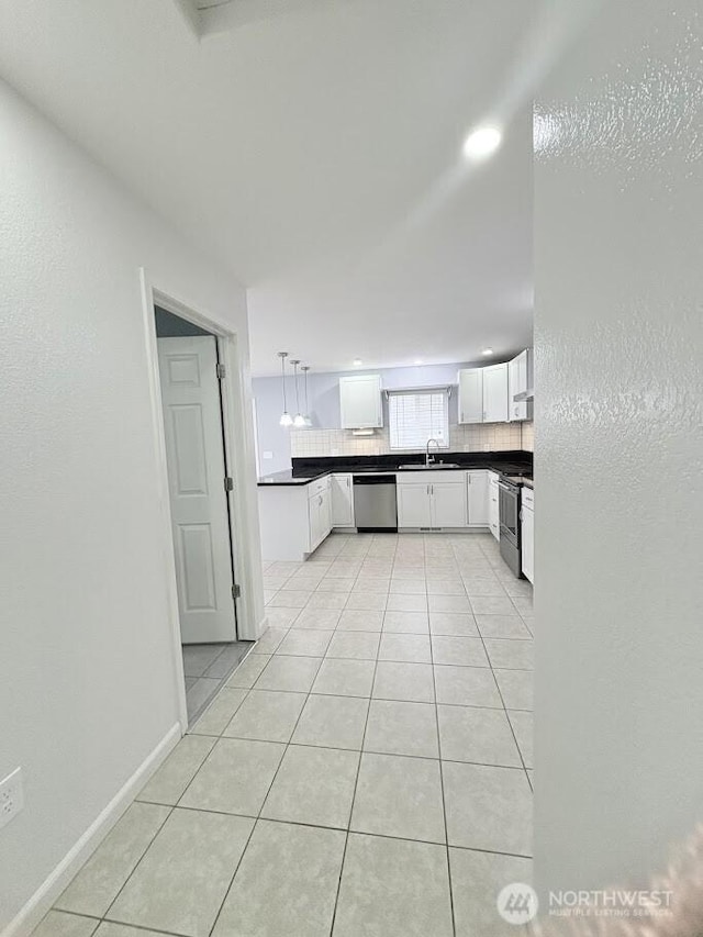 kitchen featuring a sink, dark countertops, light tile patterned floors, and stainless steel appliances