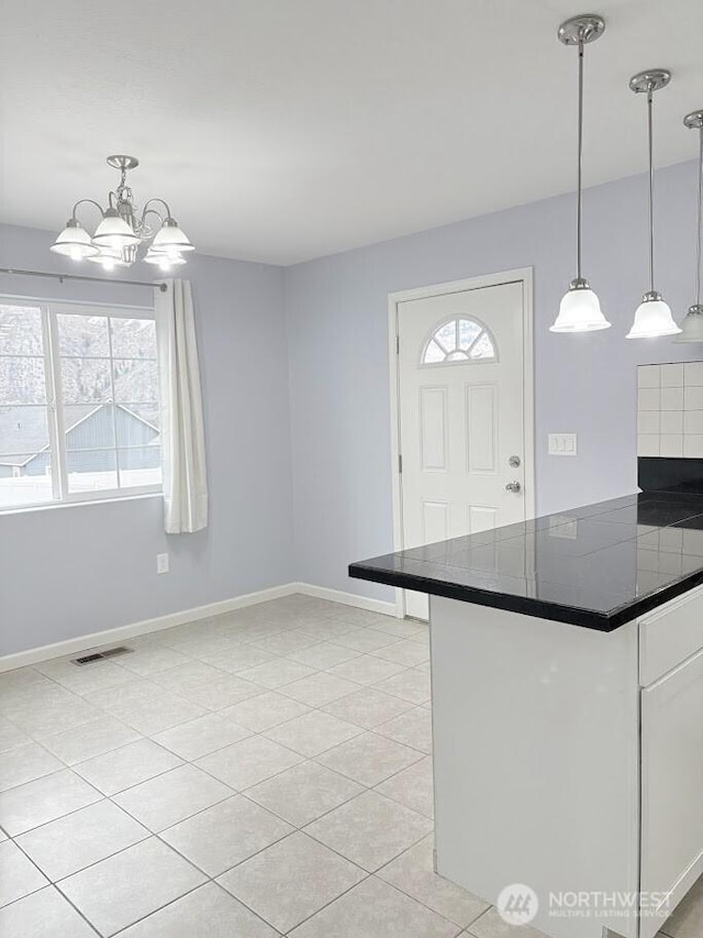 kitchen with light tile patterned floors, baseboards, visible vents, white cabinets, and dark countertops