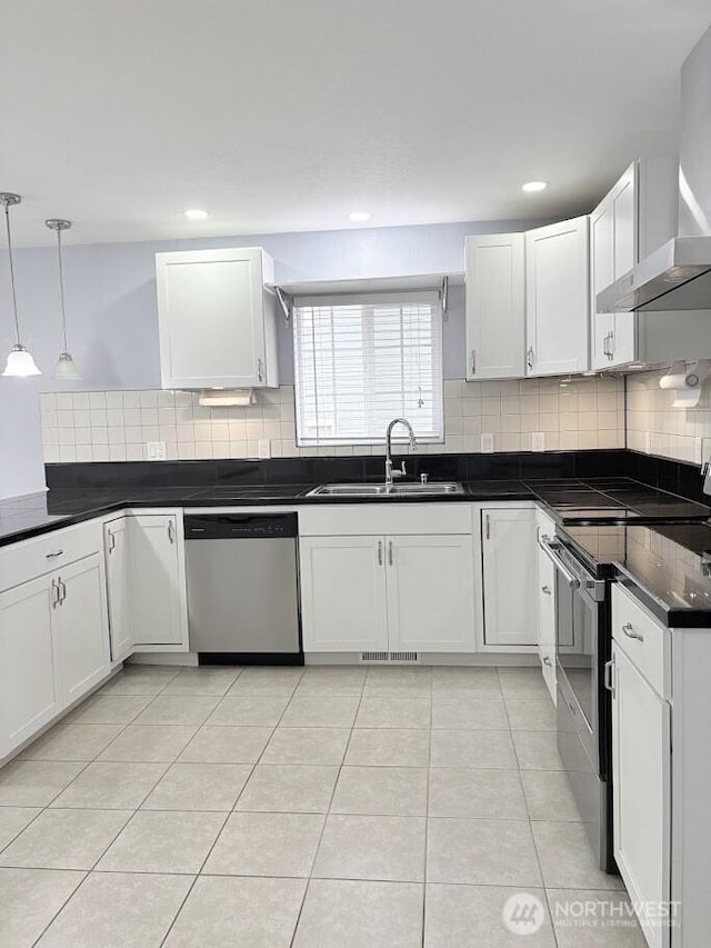 kitchen featuring a sink, dark countertops, stainless steel appliances, wall chimney exhaust hood, and light tile patterned flooring