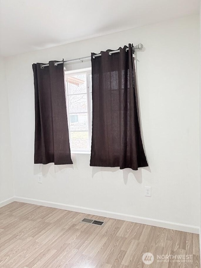 spare room featuring light wood-style flooring, baseboards, and visible vents