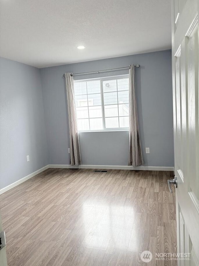 spare room featuring visible vents, baseboards, and wood finished floors