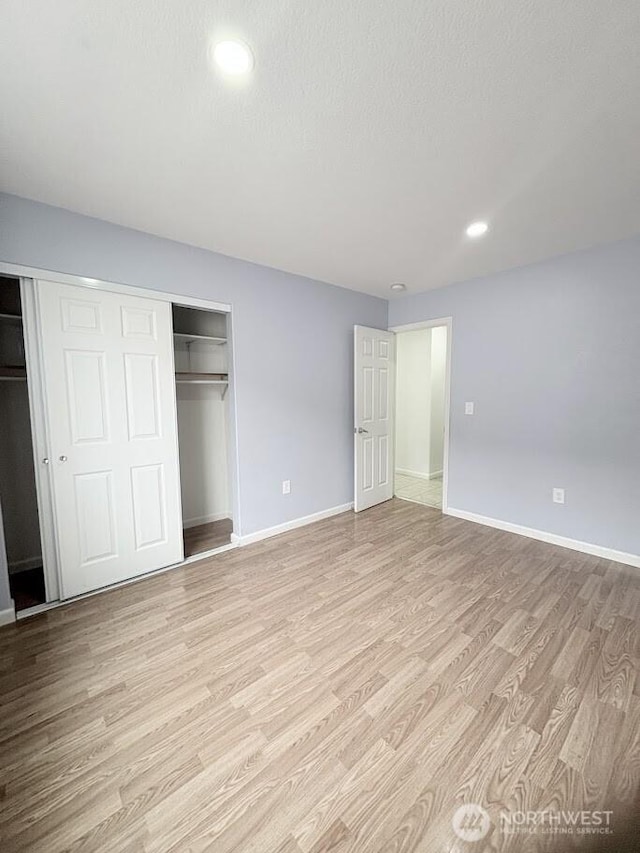 unfurnished bedroom with recessed lighting, light wood-type flooring, baseboards, and a closet