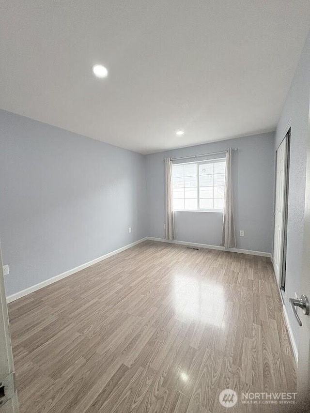 spare room featuring recessed lighting, wood finished floors, and baseboards