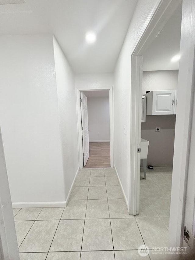 hallway with light tile patterned flooring and baseboards