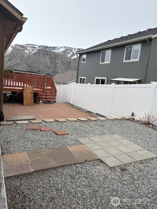 view of yard with a deck with mountain view, a patio, and fence