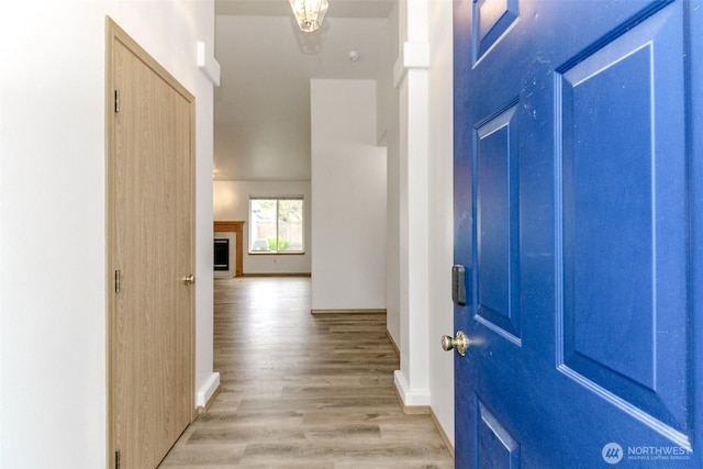 entrance foyer featuring light wood finished floors, a fireplace, and baseboards