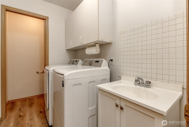 washroom with a sink, cabinet space, light wood-style floors, and independent washer and dryer