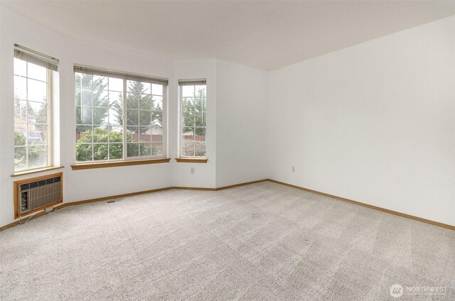 unfurnished room featuring heating unit, carpet flooring, visible vents, and baseboards