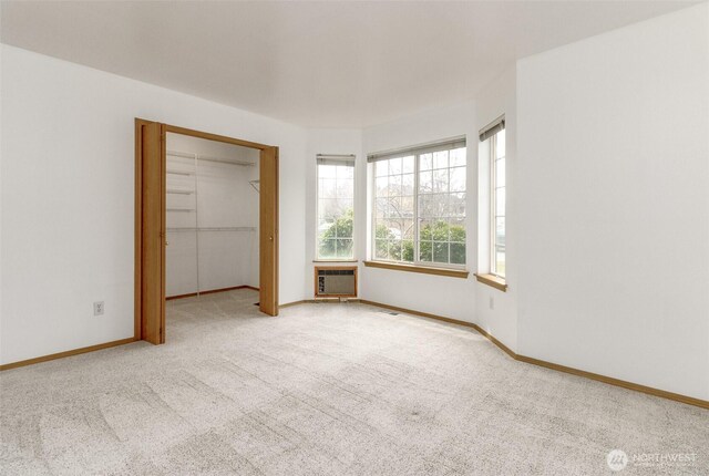 unfurnished bedroom featuring a wall mounted air conditioner, baseboards, carpet floors, and a closet