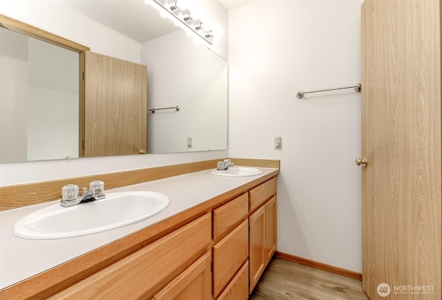 full bath with a sink, baseboards, wood finished floors, and double vanity