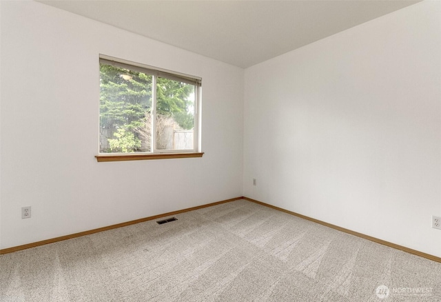 spare room with visible vents, baseboards, and light colored carpet