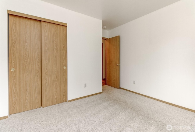 unfurnished bedroom with carpet, a closet, and baseboards