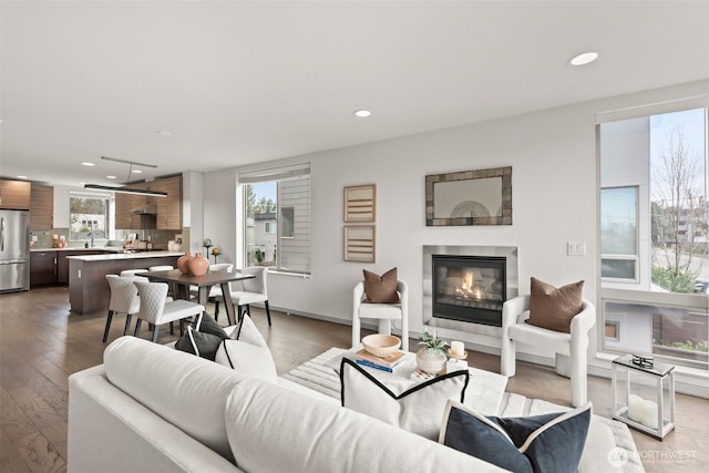 living area with recessed lighting, light wood-type flooring, and a glass covered fireplace