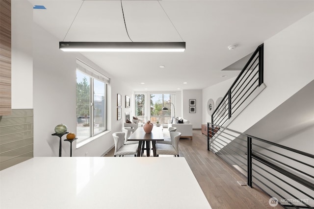 dining room with recessed lighting, stairway, a healthy amount of sunlight, and wood finished floors