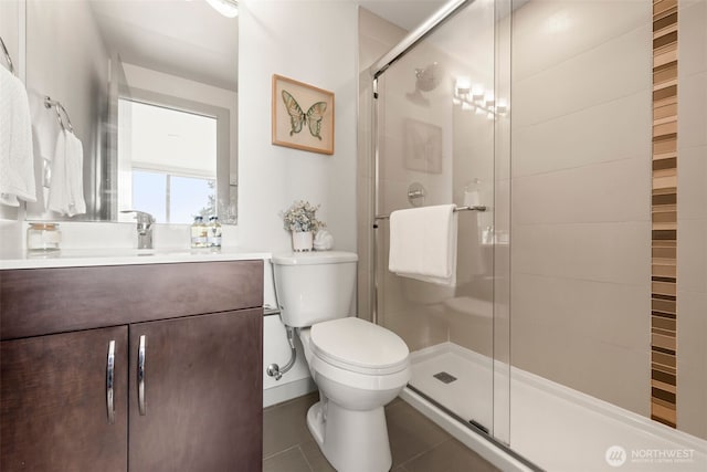 bathroom with vanity, toilet, a stall shower, and tile patterned flooring