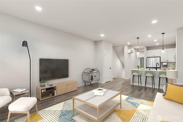 living area featuring recessed lighting, light wood-type flooring, and a wall mounted air conditioner