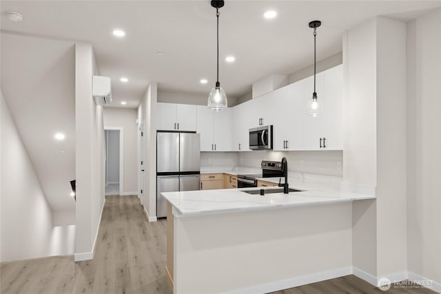 kitchen with light wood finished floors, a peninsula, stainless steel appliances, and a sink